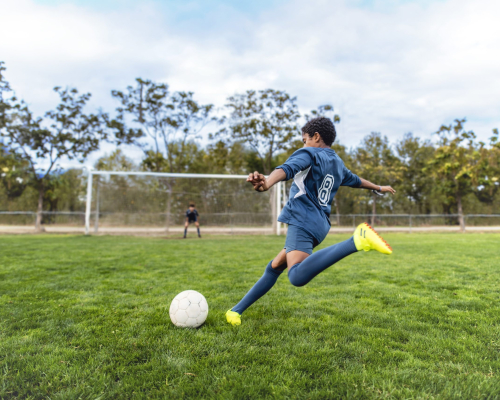 Athletic Mixed Race Boy Footballer Approaching Ball for Kick